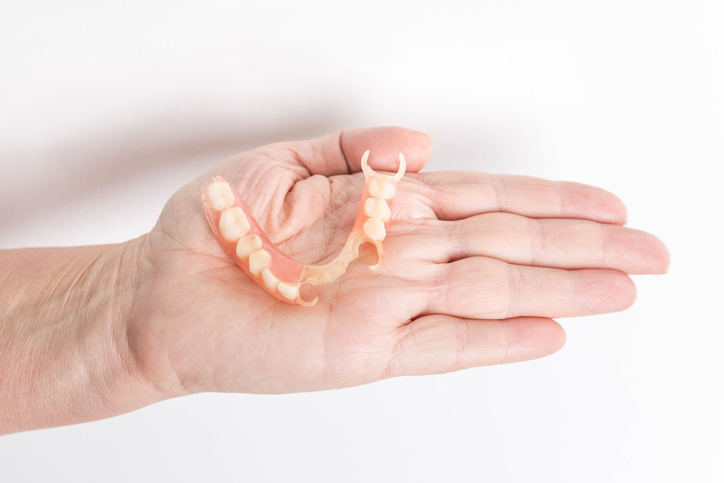 Hand holding a dental partial denture.